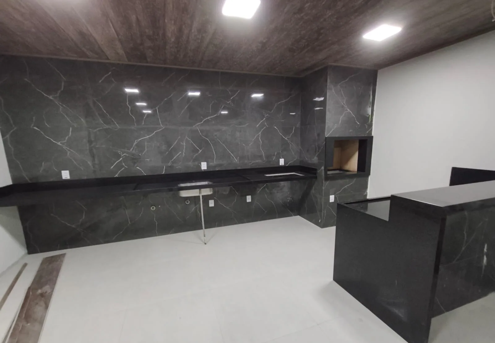 Vista ampla de area gourmet com paginacao continua de marmore preto do piso ao teto