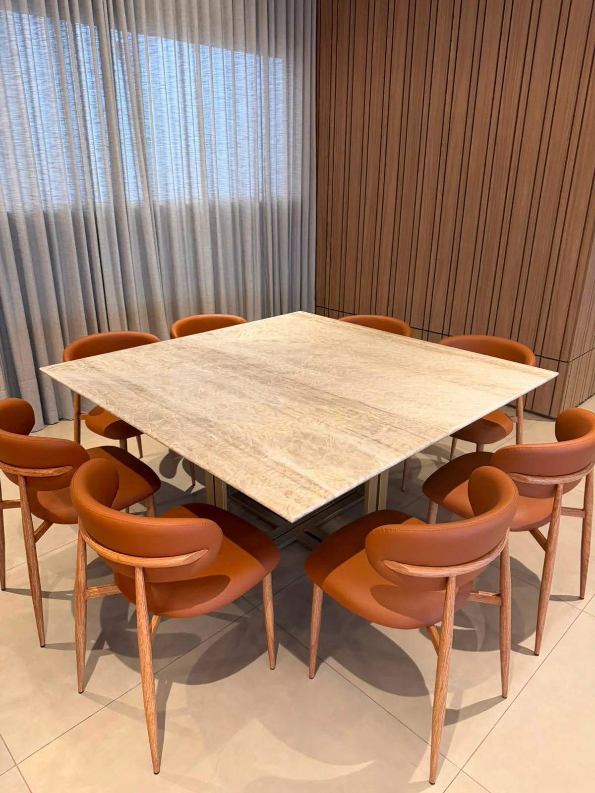 Mesa de jantar quadrada em travertino sobre base metalica, com oito cadeiras em couro caramelo